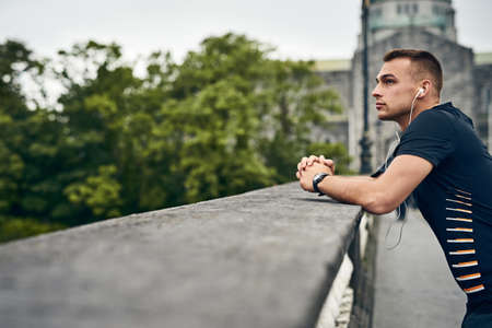 Setting new goals for himself. Shot of a sporty young man taking a break while exercising outdoors.