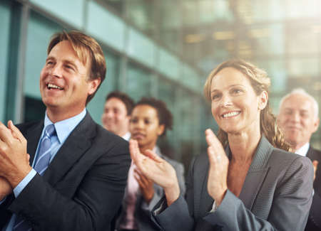 Well done. Cropped shot of a group of businesspeople applauding while sitting in a presentation.の写真素材