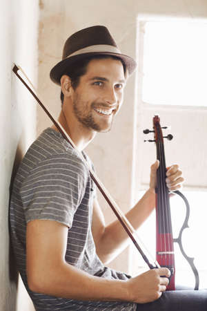 Ready to make some music. Handsome young musician holding his violin on a stairwell.の写真素材