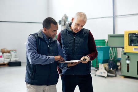 Supervising operations has never been easier. Shot of two factory managers doing a warehouse...