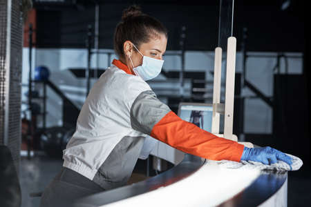 Regular cleaning is key to prevent the spread of germs. Shot of a young woman cleaning the reception...