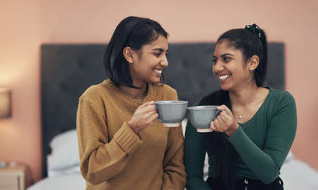 Theres no one else Id rather spill some tea with. Shot of two young women drinking coffee while sitting together at home.の写真素材