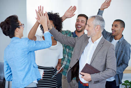 Successful and loving it. Shot of a group of happy coworkers high-fiving while standing in an...