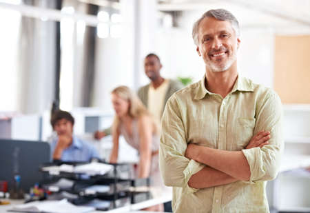 His business ideas are groundbreaking. Shot of a mature businessman with his colleagues blurred in the background.の写真素材
