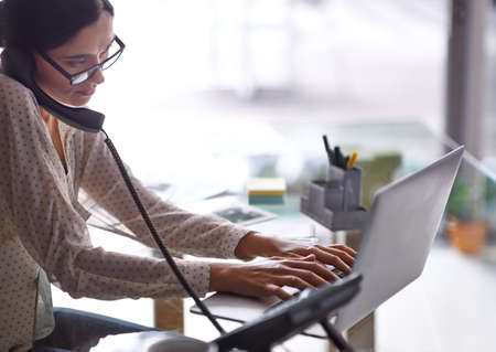 Doing it all at once. Shot of a beautiful young businesswoman working at her desk.