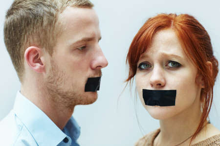 Theyve been silenced. A young couple looking sad with tape over their mouths.の写真素材