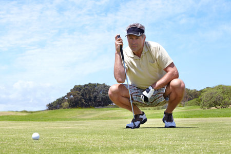 Lining up his shot. A mature man lining up his putt on the green.の写真素材