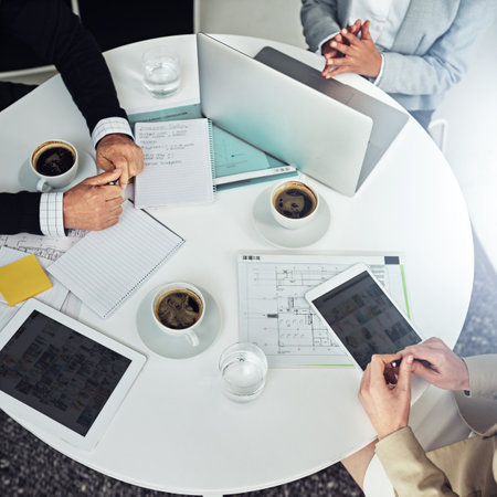 All hands on deck for the project. High angle shot of a group of businesspeople working together around at table in an office.の写真素材