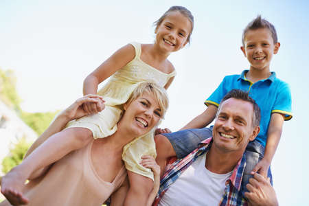 A happy loving family. A portrait of two happy parents carrying their young kids on their shoulders...