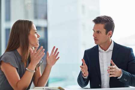 Talking some serious business. Cropped shot of two businesspeople having a discussion in the office.の写真素材