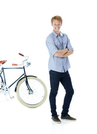 Getting around in style. A handsome young red-headed man standing next to an old-fashioned bicycle with his arms folded.の写真素材