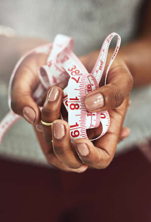Made to measure. Cropped shot of an unrecognizable fashion designer holding measuring tape.の写真素材