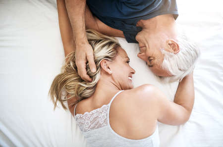 Love - you have to feel it to know what it is. Shot of an affectionate mature couple lying in bed together at home.の写真素材