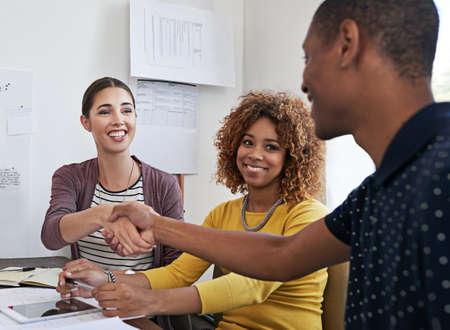 Were eager to see what you can offer our business. Shot of coworkers shaking hands during a meeting...