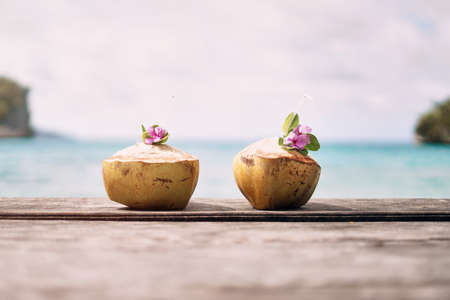 Care for a drink my love. Still life shot of two coconuts placed alongside each other on a beach in...
