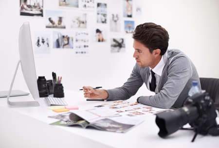 Making his final selection. A photographer looking at his images in his office.