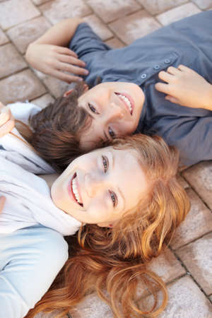 They do everything together. Portrait of a brother and sister lying on the floor with their heads together.の写真素材