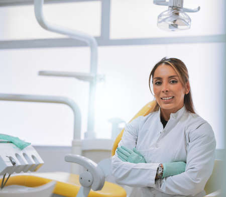 How can I help today. Portrait of a cheerful young female dentist standing with her arms folded...