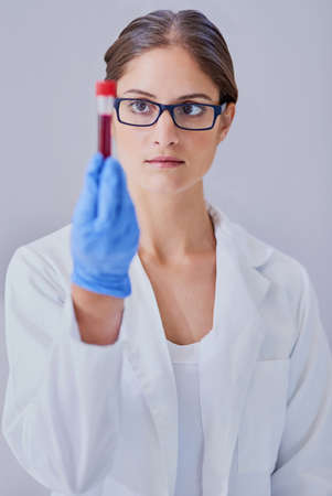 She holds the key to the cure. Shot of a scientist examining a medical sample while standing in a laboratory.の写真素材