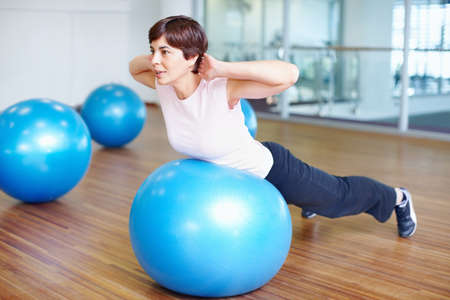 Fitness exercise. Woman doing fitness exercise using pilates ball.の写真素材