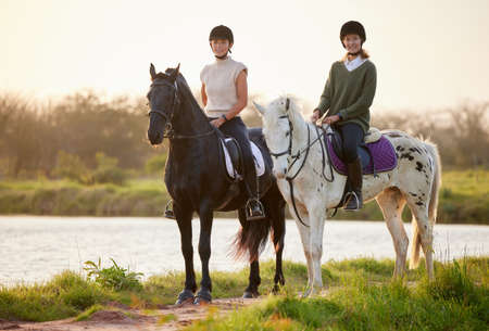 Horses are powerful yet majestic. Shot of two young women riding their horses outside on a field.の写真素材