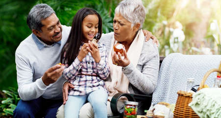 We always have healthy treats for her. Shot of a cheerful little girl sitting down on a bench with...