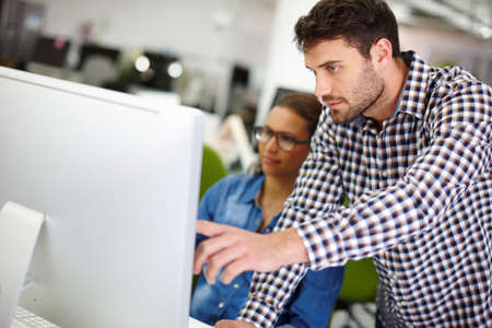 Just click here quick. Cropped shot of a handsome young man assisting a female colleague with...