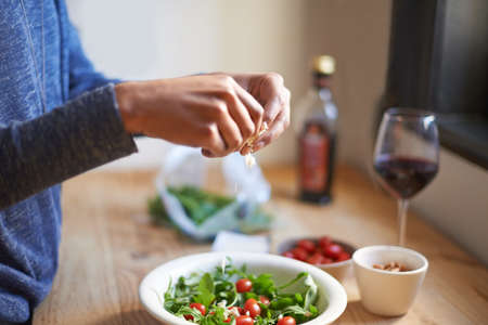 Creating the perfect lunch. A young woman making a salad in her kitchen.の写真素材