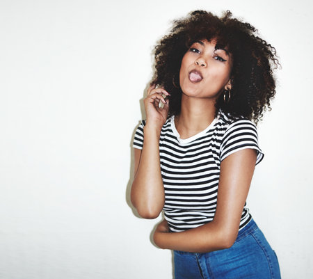 Shes charmingly cheeky. Studio shot of a young woman playfully sticking her tongue out against a...