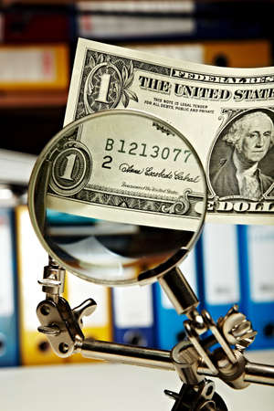 Zooming in on money issues. A dollar bill being magnified by a magnifying glass.の写真素材