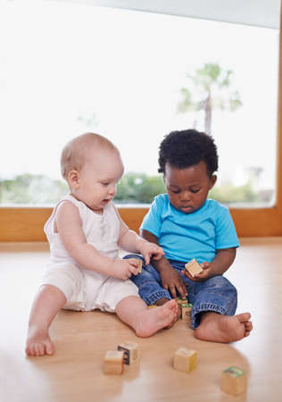 Learning and growing together. A shot of two adorable babies playing with building blocks.