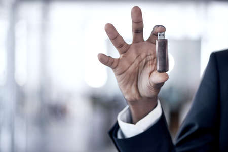 These things are so efficient. Cropped shot of an african businessman holding up a usb.の写真素材