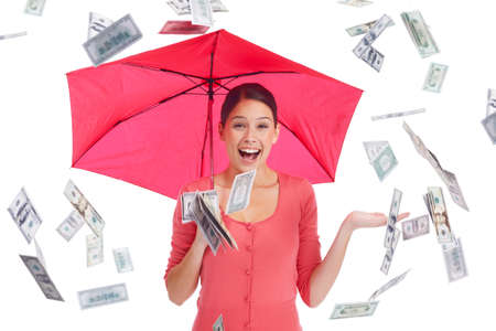 What we all want. Pretty young woman under a red umbrella with money showering down.の写真素材