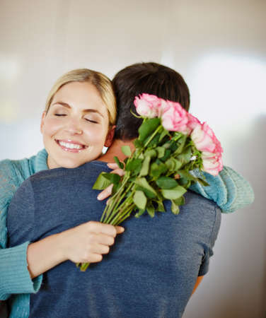 You just made my day. Shot of an affectionate young man giving his beautiful young wife a bouquet of pink roses.の写真素材