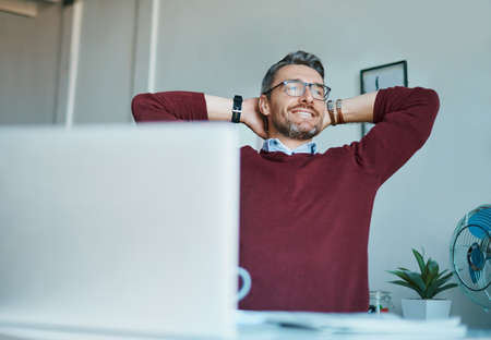 Accomplishment is a satisfying feeling. Shot of a mature businessman taking a break at his office...