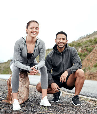 It all starts with getting out there and making the change. Portrait of a sporty young man and woman taking a break while exercising outdoors.の写真素材