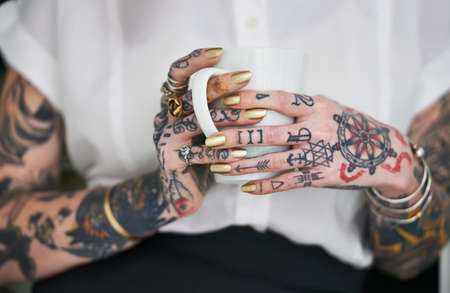 She loves her tattoos. Shot of an unrecognizable tattooed businesswoman holding a mug.の写真素材