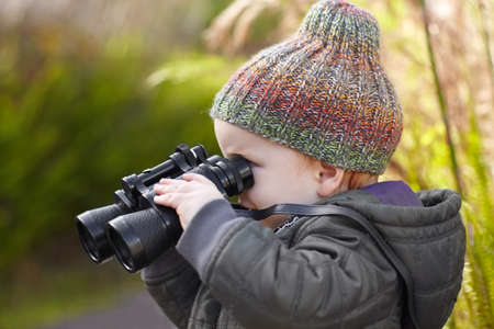 He has a growing appreciation for teh great outdoors. A cute little boy looking through binoculars.