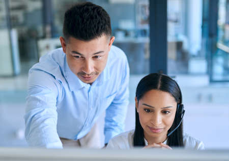 Passing the torch of customer service expertise. Shot of a young man helping his colleague in a...