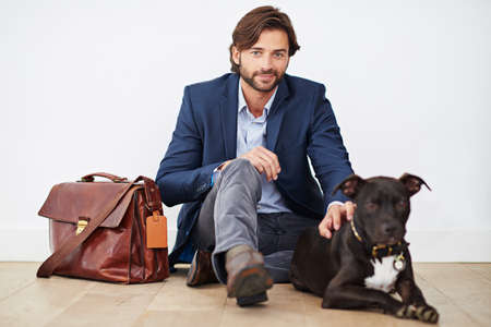 Happiness is coming home to your dog. Shot of a handsome man spending time with his dog after a day...
