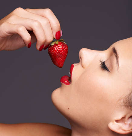 Sensuous strawberries. Closeup portrait of a beautiful young woman with strawberry in her mouth.の写真素材