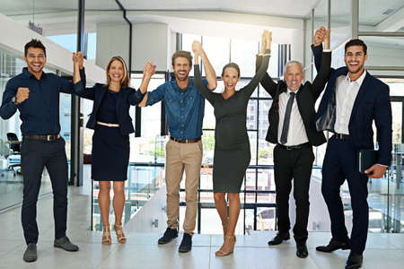 Celebrating another corporate success. Portrait of a confident looking team of coworkers sheering...