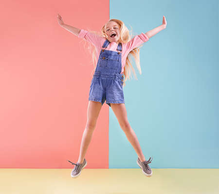 Wheee. A cute little girl jumping against a colorful background.