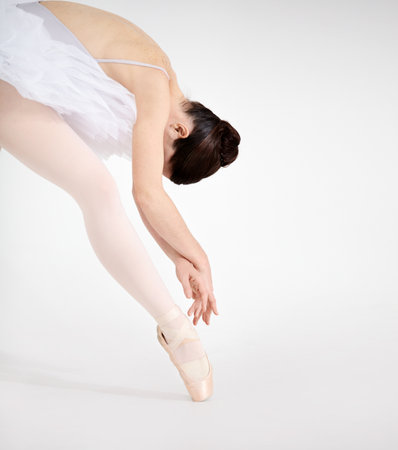 Nothing but elegance. Dedicated young ballerina dancing en pointe against a white background.の写真素材