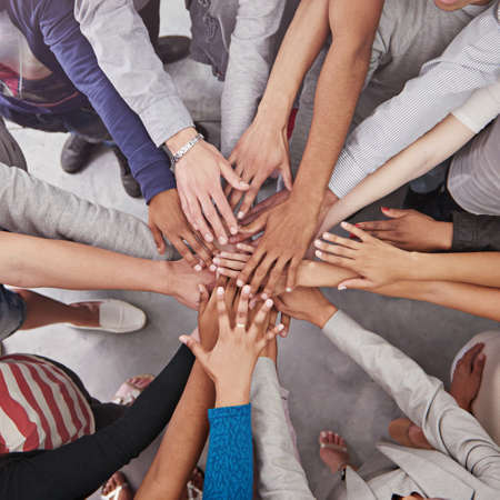 All for one and one for all. Cropped shot of a business team standing in a circle with their hands stacked.の写真素材