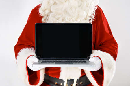 Now you can type your wish list. Cropped portrait of Father Christmas holding a laptop - isolated on white.の写真素材