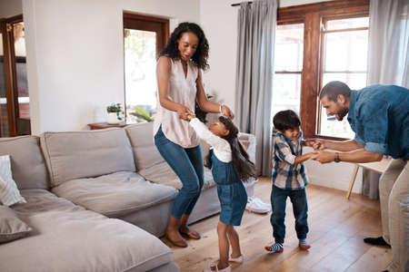 This is how this family starts the weekend. Shot of a family of four dancing together at home.の写真素材