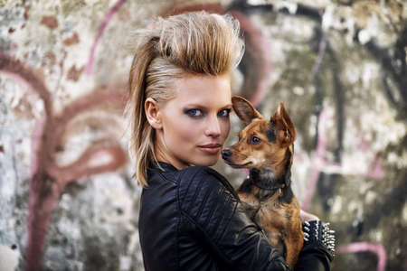 Urban dog. A young trendy woman holding a small dog in an urban setting.の写真素材