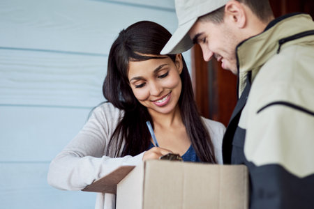 Your signature is all I need. Cropped shot of a young woman signing for her delivery from the courier.の写真素材