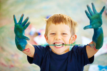 Messy little artist. A little boy covered in paint.の写真素材
